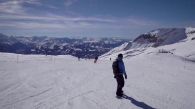 Snowboardcular güzel alp yamaçlarında gezerler. Güneşli kış günü.