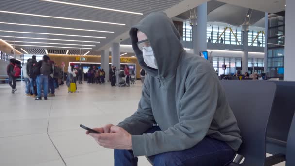 Un hombre en la sala de espera del aeropuerto internacional. Las protecciones deben usarse durante una epidemia . — Vídeos de Stock