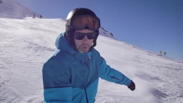 Retrato de un snowboarder feliz en una ladera de montaña. El hombre baja y se regocija. . — Vídeos de Stock