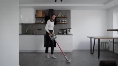 Şık bir mutfakta temizlik yapmak. Bir kız yerleri süpürüyor.