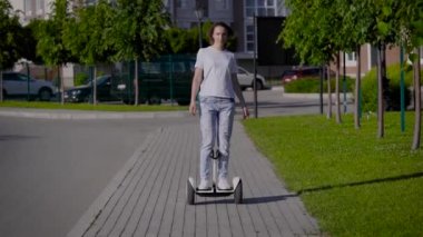İnce, genç bir kız şehir caddesi boyunca jiroskoplu scooter kullanıyor. Modern elektrik taşımacılığı.