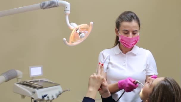 病人向牙医作检查和清洁牙齿的肖像 牙科医生用镜子检查一位年轻妇女的牙齿 — 图库视频影像