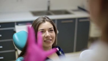Diş hekimi ve hasta, arka planda tıbbi ekipmanlarla yapılan bir muayenede tedaviyi seçiyor