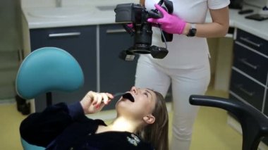 Kameralı diş hekimi hastaları tedaviden sonra gülümsetiyor. Gölgesiz flaş yüzüklü özel kamera.