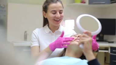 Esmer, dişçinin ofisindeki aynaya bakıyor. Çekici bir genç adam dişçinin çalışmalarını değerlendiriyor. Güzel doktor müşterisinin yanında oturuyor.