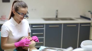 Diş hekimi, dişçi muayenehanesinde hoş bir ortamda bir kadını tedavi ediyor. Ofiste her türlü diş hastalığını tedavi etmek için özel ekipmanlar vardır..