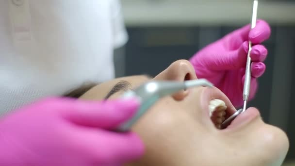 身穿白衣的牙科医生用专业设备治疗女孩的牙齿 — 图库视频影像