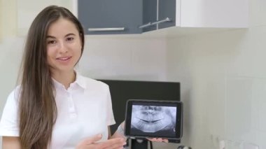 Elinde tablet olan dişçi kız, dişlerini tedavi ediyor.