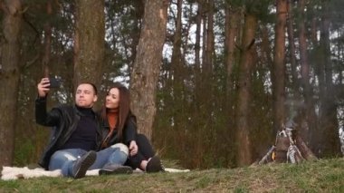Birbirlerine aşık çiftler ateşin yanında selfie çekiyorlar.
