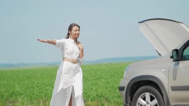 Kaputu patlamış arabanın yanındaki stresli genç kadın sürücünün yardım bekleyen aracıyla ilgili bir arıza sorunu var..