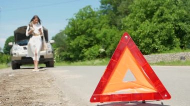 İş kadını yol kenarında bozuk bir şekilde arabasının yanında yardım bekliyor. Arızalı arabasıyla, acil servisle yolda sorun yaşıyor.