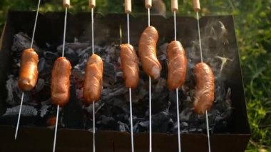 Piknikte aile tatili, barbekü yemekleri, ızgarada pişmiş sosisler. Izgara sıcak tütsülenmiş.