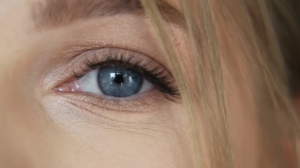 衣服漂亮女人的眼睛 年轻的蓝眼睛女孩 宏观拍摄 女性的脸眨眼 看着相机 慢动作 — 图库视频影像