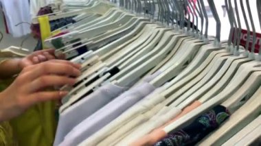 Kadın Hands Giyim Askıları raylı raf üzerinde çalışan ve giysi mağazası 'nda elbise arıyorum.