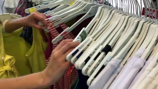 女性手在衣架的铁架上奔跑 并在服装店寻找服装 — 图库视频影像