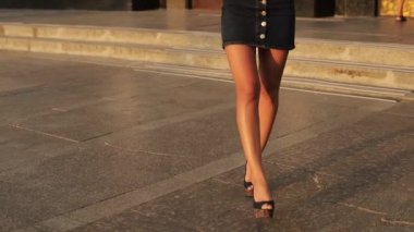 Yüksek topuklu seksi bacaklar. Romantik bir kadın bulvarda yalnız yürüyor. Yaz sezonunda kısa elbiseli çekici bir kız. Yavaş çekim.