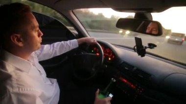 Araba kullanırken içki içen sorumsuz genç bir işadamı. Araba kullanırken bira içen erkek sürücü