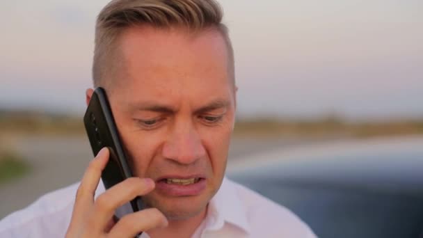 Man Zenuwachtig Aan Het Bellen Aan Telefoon Bij Auto Buiten — Stockvideo