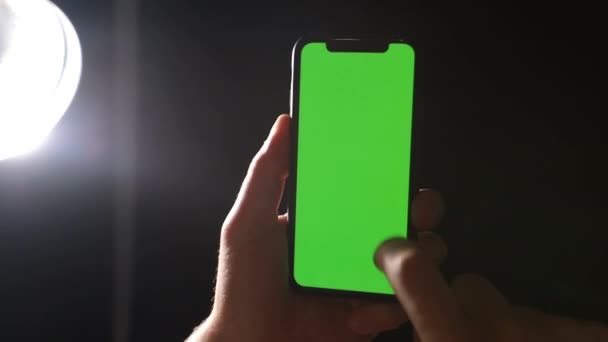 Το χέρι του ανθρώπου χρησιμοποιεί ένα smartphone με πράσινο chromakey οθόνης σε μαύρο φόντο — Αρχείο Βίντεο