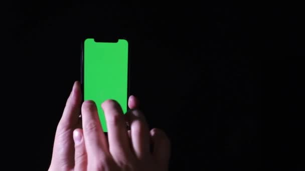 黒の背景に緑の画面のクロマキーを持つスマートフォン — ストック動画