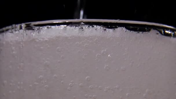 Carbonated water in a glass on a black background, a refreshing carbonated drink — Stock Video