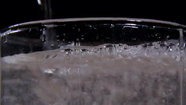 Nahaufnahme von kohlensäurehaltigem Wasser in einem Glas auf schwarzem Hintergrund — Stockvideo