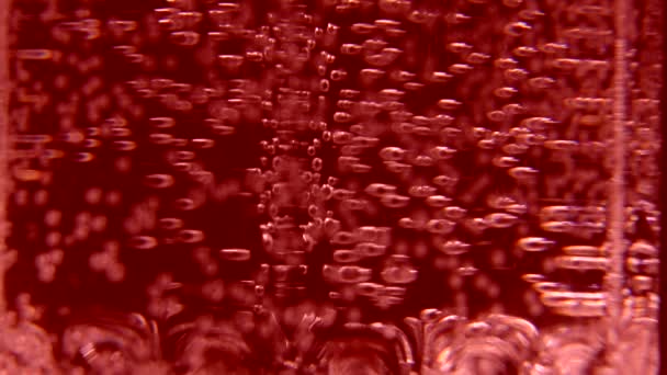 Agua carbonatada roja en un vaso sobre un fondo negro — Vídeos de Stock