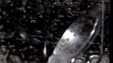 Siyah arka planda şeffaf bir fincanda şekeri karıştırmak