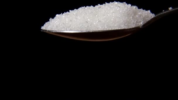 Colher de açúcar em um fundo preto — Vídeo de Stock