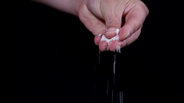 Kézzel szórja só egy fekete háttér. — Stock videók