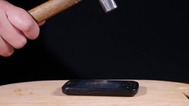 Op de tafel ligt een mobiele telefoon die kapot gaat door hamerslagen.. — Stockvideo