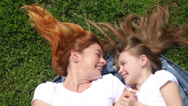 Mom and daughter lying or resting on the grass in the park — Stock Video