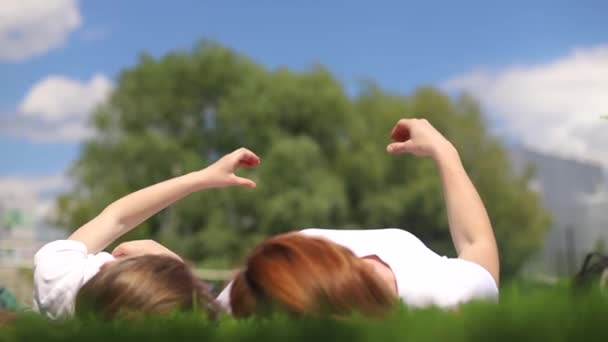 Mamma och dotter ligger eller vilar på gräset i parken — Stockvideo