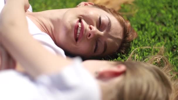 Мама и дочь лежат или отдыхают на траве в парке — стоковое видео
