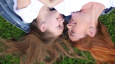 Anne ve kızı banliyö parkında yeşil çimlerin üzerinde yatıyor..