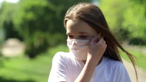 Ein kleines Mädchen entfernt nach einer Coronavirus-Pandemie eine medizinische Maske. — Stockvideo