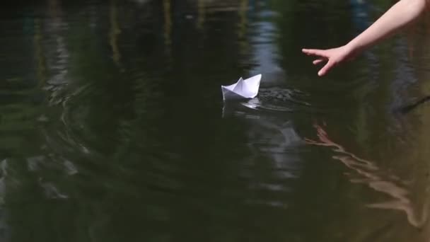 Little girl playing in a puddle with a paper boat, slow motion — Stock Video