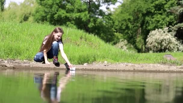 Little girl playing in a puddle with a paper boat, slow motion — Stock Video