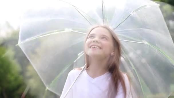 Маленькая девочка ходит с прозрачным зонтиком в руках — стоковое видео