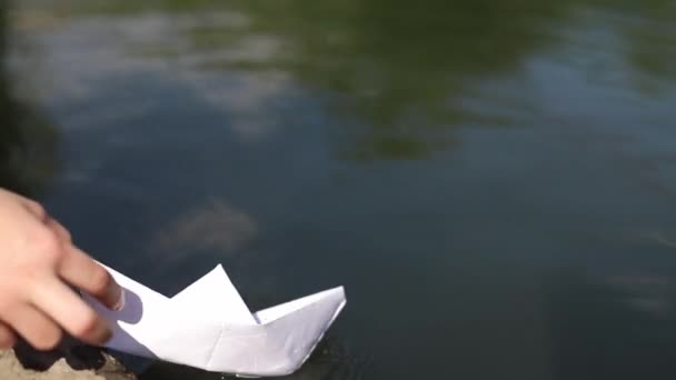 Adolescente brincando com um barco de papel em um parque da cidade . — Vídeo de Stock