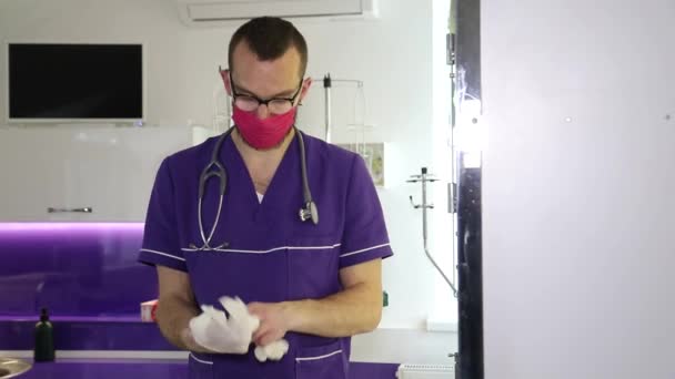 De arts trekt handschoenen aan en bereidt zich voor op het onderzoek van de patiënt — Stockvideo