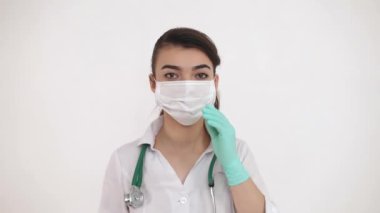 Genç bir doktor koronavirüs salgınına karşı koruyucu bir maske takar (COVID-19).