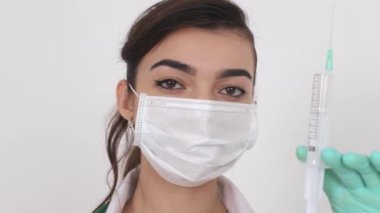 Koronavirüse karşı aşısı olan bir şırıngayı elinde tutan tıbbi maskeli bir virüs uzmanı (COVID-19), aşı Coronavirus Covid-19 virüsü