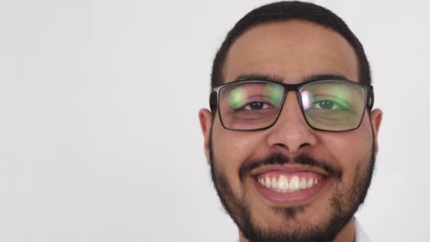 Egy fiatal arab férfi mosolygós arca közelről. Egy boldog ember egyenesen a fényképezőgépbe néz. — Stock videók
