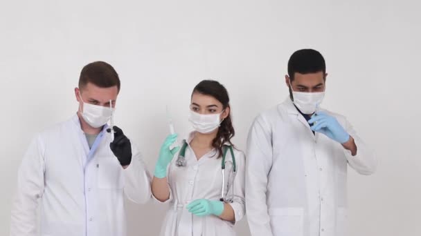 Medizinstudenten aus verschiedenen Ländern auf weißem Hintergrund. Glückliche Medizinstudenten mit Spritzen in der Hand — Stockvideo