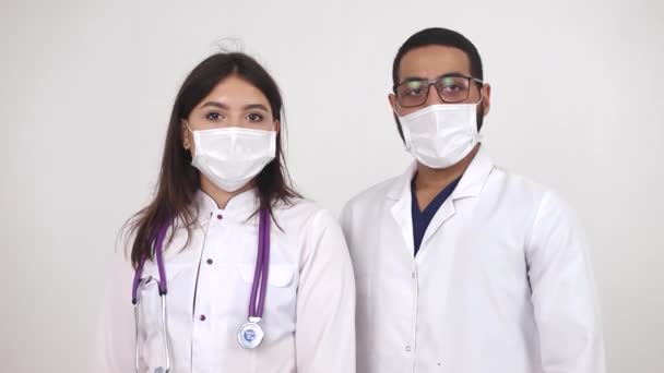 Két fehér köpenyes orvos, fehér háttérrel. Afrikai és európai orvosok — Stock videók