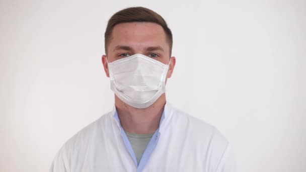 의료 마스크를 쓴 젊은 의사가 카메라를 봅니다. 코로나 바이러스와 세계적 유행병으로부터의 안전 한 생활에 대한 개념. — 비디오