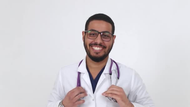 Un médico árabe alegre en una bata de laboratorio se pone gafas — Vídeos de Stock