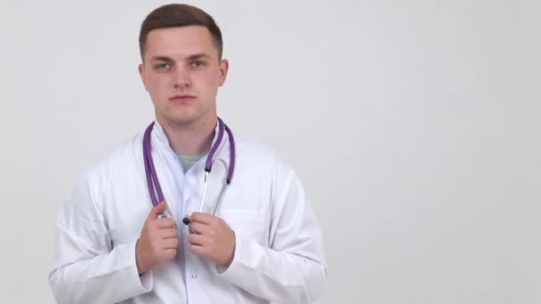 Um jovem médico de casaco branco aponta um dedo para o topo . — Vídeo de Stock
