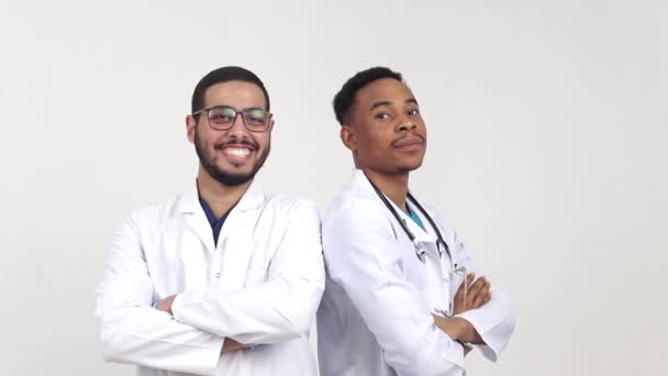 Dois jovens médicos olham para a câmera e sorriem — Vídeo de Stock